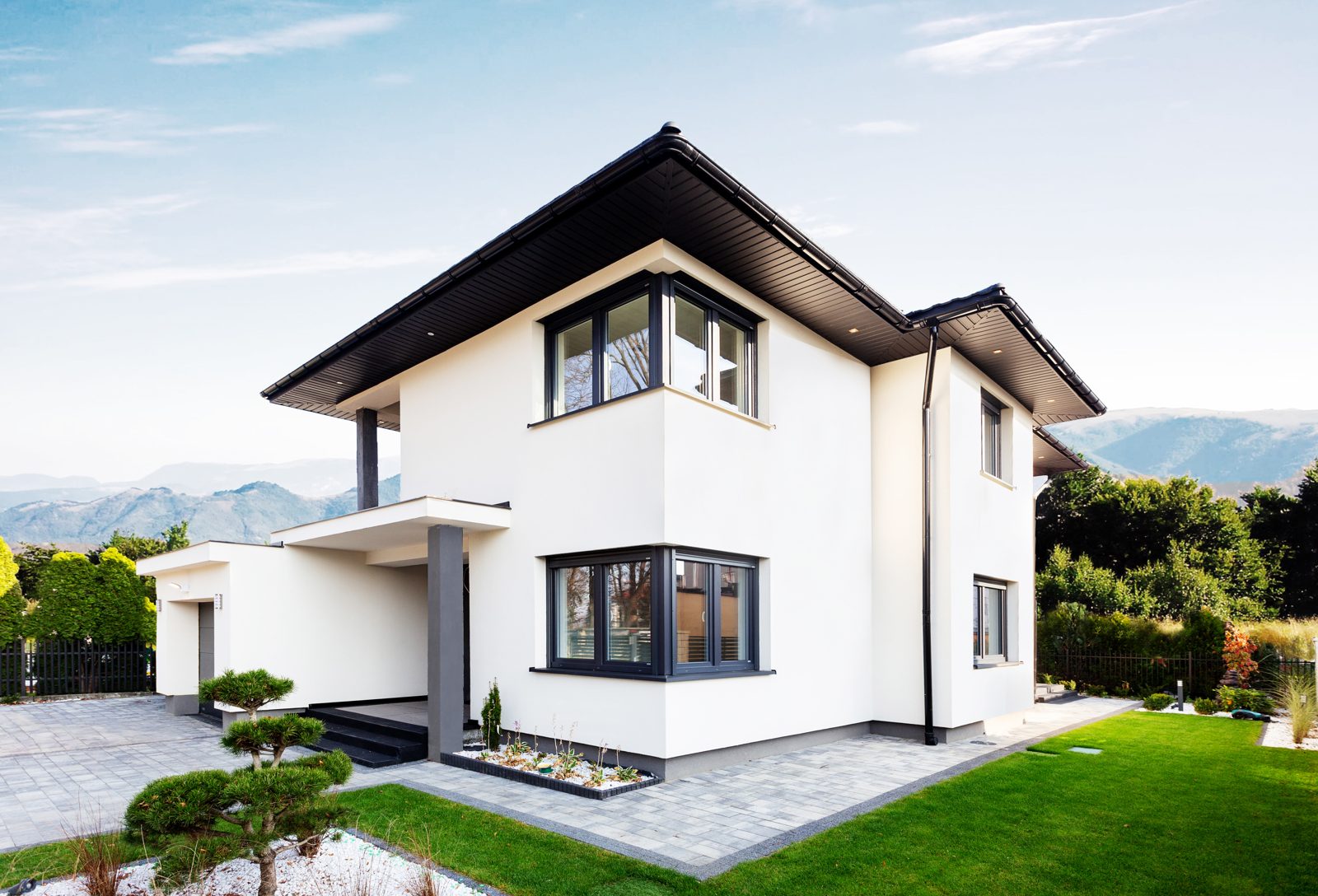 Two-storey white rendered house with dark grey corner windows