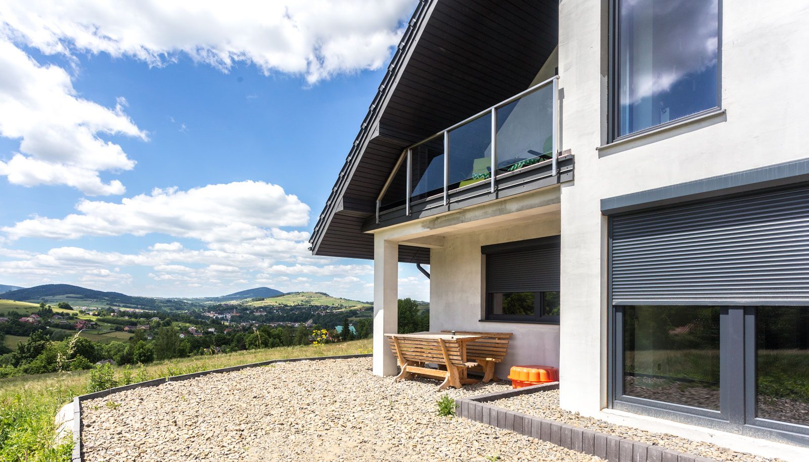 Hillside house with dark grey windows and roller shutters